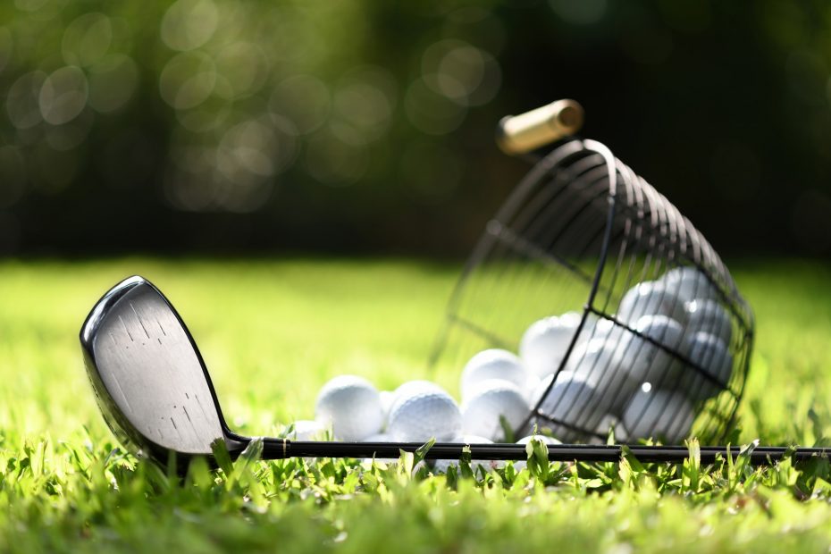 Golfklubb och korg med golfbollar
